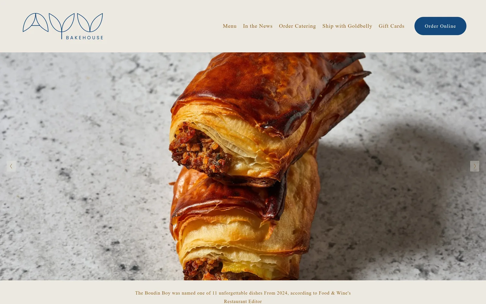 ayubakehouse.com, bakery website design: a cream header with a navy leaf monogram and pill button sits above a close crop of two flaky