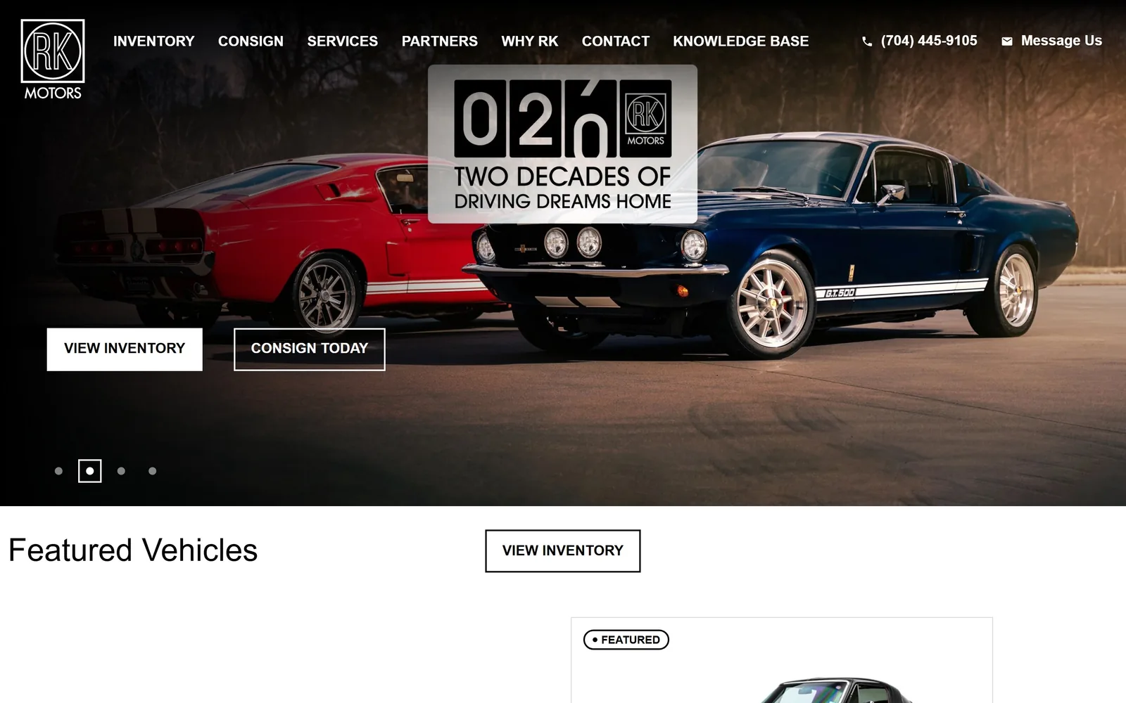 rkmotors.com, car dealership website design: a red and a blue Shelby GT500 at dusk, a 20th anniversary odometer badge floating between them