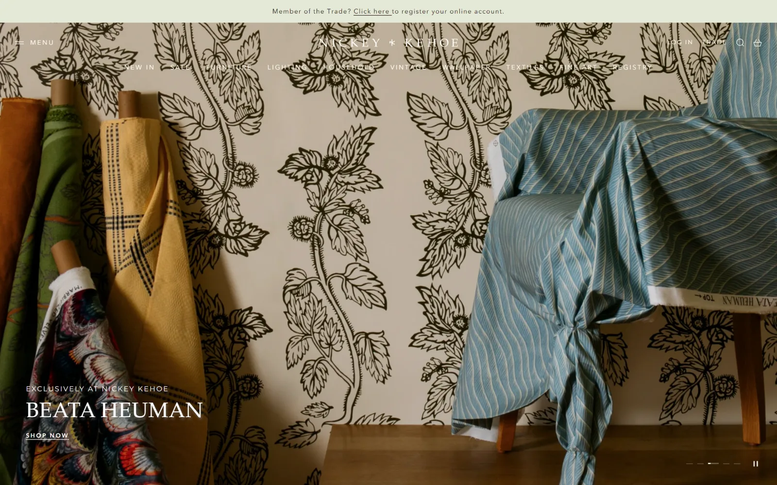 nickeykehoe.com, ecommerce website design: bolts of fabric lean against patterned wallpaper beside a draped chair
