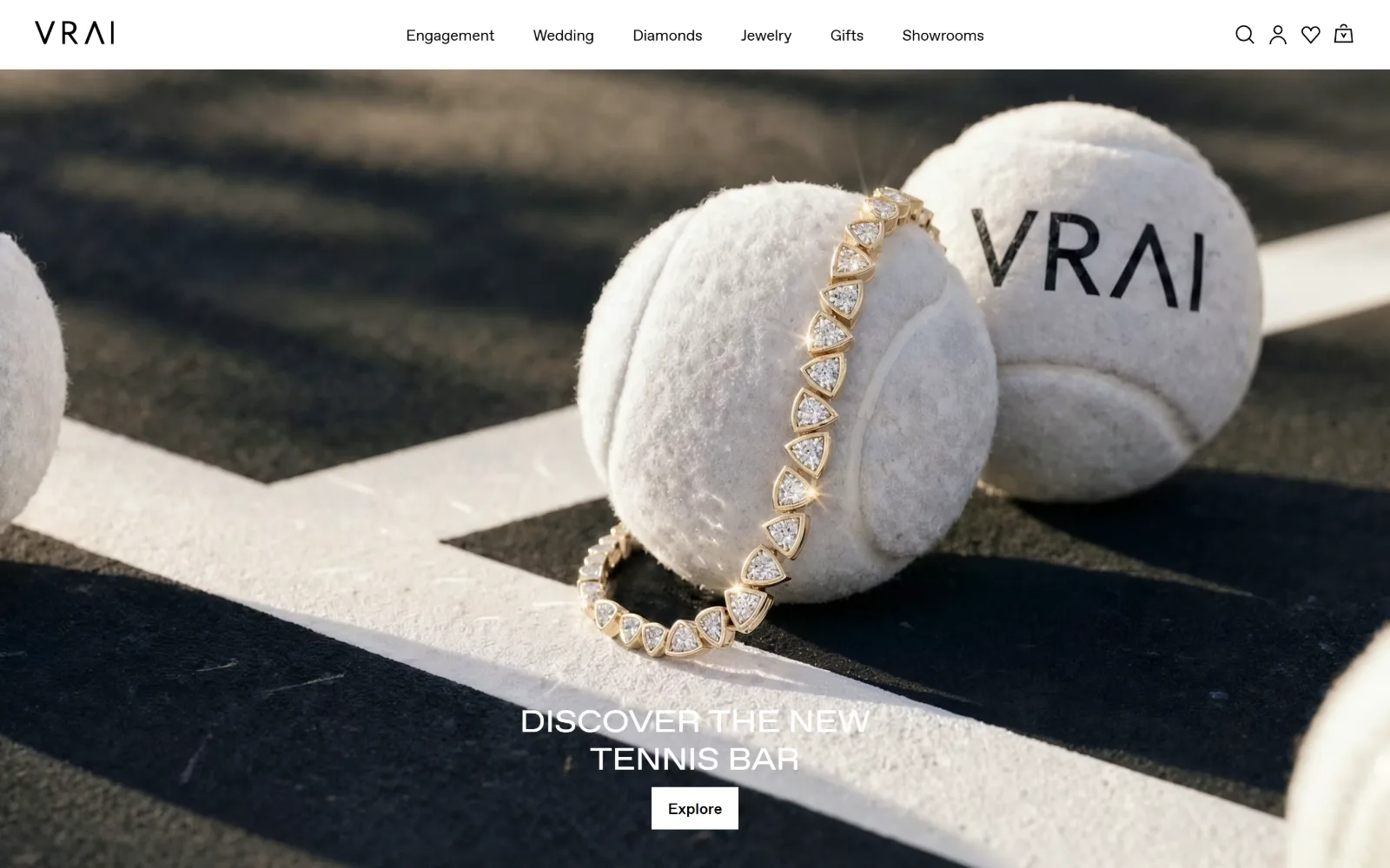 vrai.com, jewelry store website design: diamonds set in a gold bracelet drape over two tennis balls on a court line in low sun