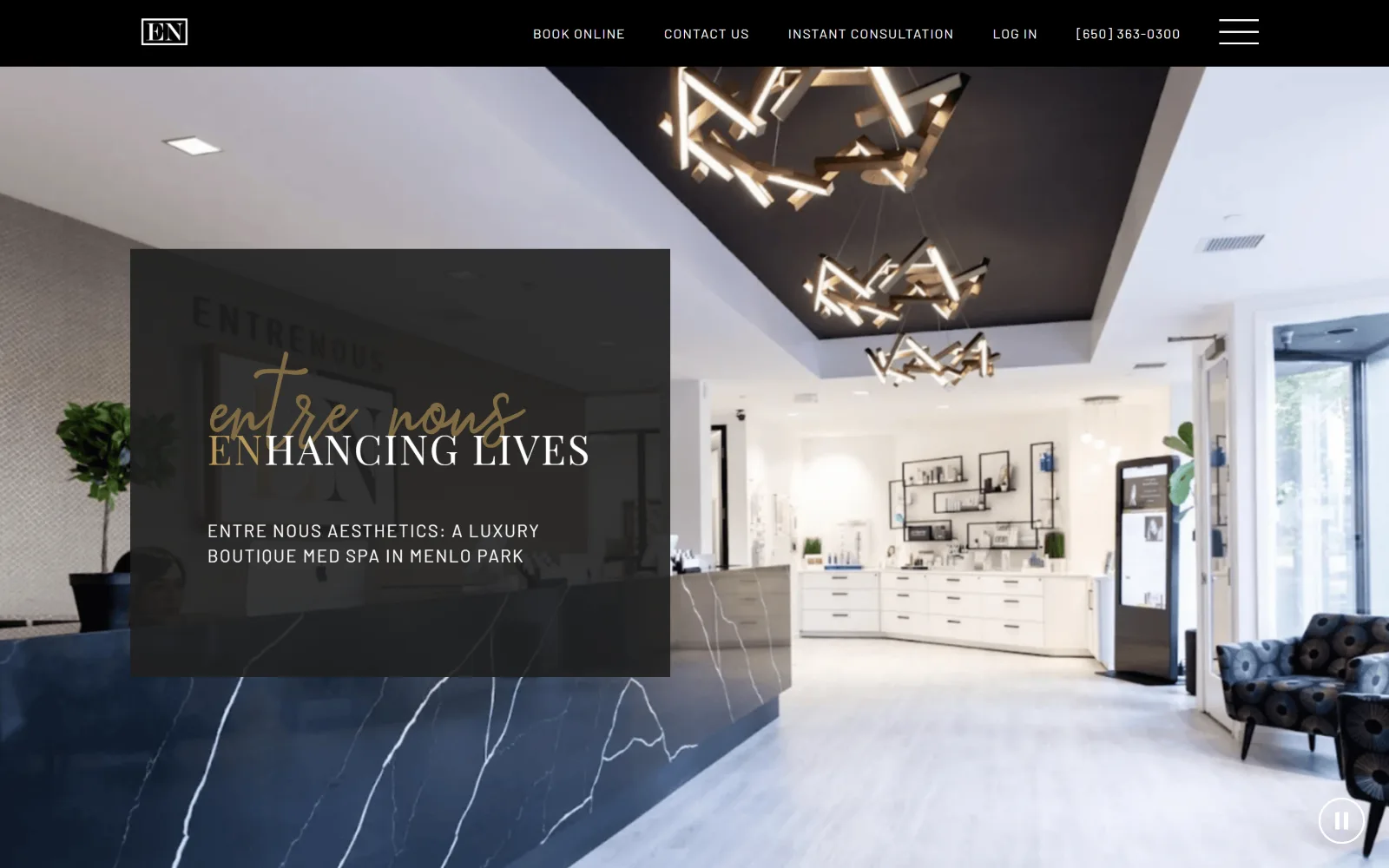 enaesthetics.com, med spa website design: wide across the frame, a bright reception with a navy marble desk and sculptural lights