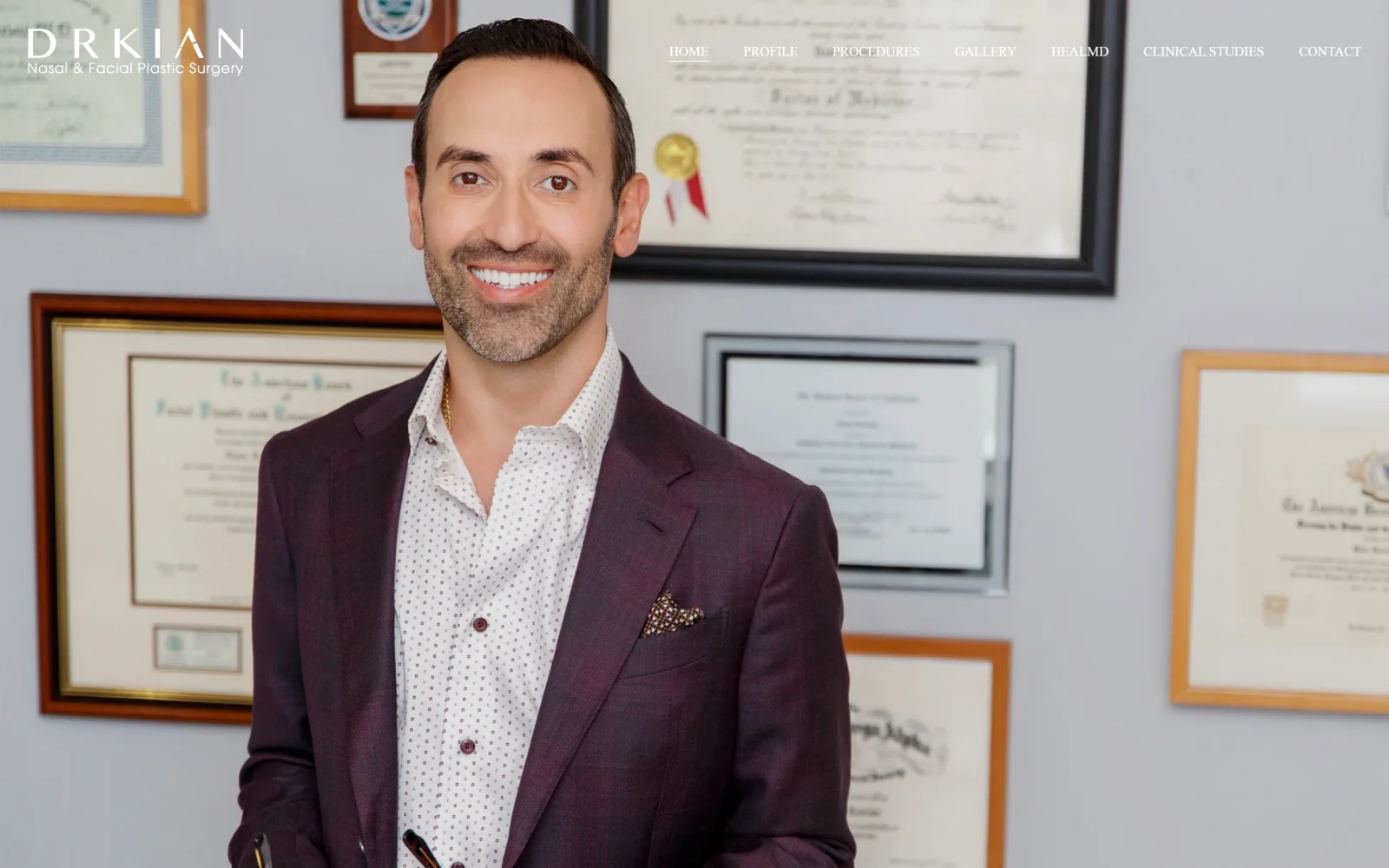 drkian.com, plastic surgery website design: full-bleed photograph of the surgeon in a plum jacket before a wall of framed diplomas