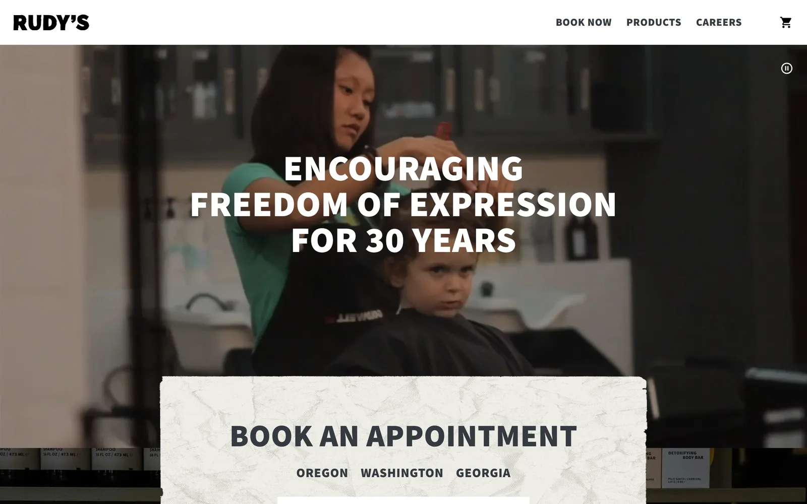 rudysbarbershop.com, salon website design: a barber cutting a boy's hair on video, three lines of heavy white caps