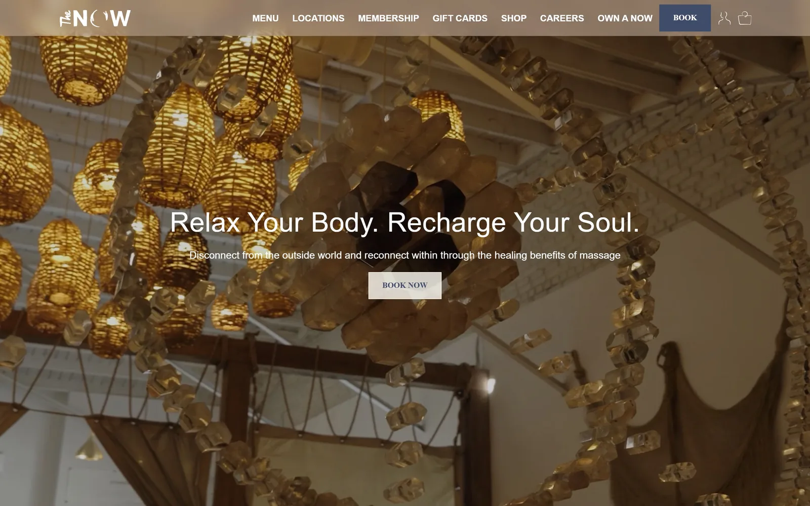 thenowmassage.com, spa website design: backlit citrine crystal chandelier footage behind a 48px white headline and a small cream Book Now