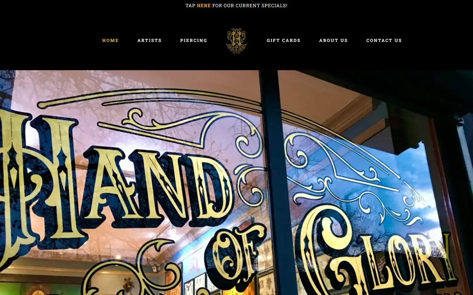 handofglorytattoo.com, tattoo website design: gilded gold window lettering shot from the pavement fills the frame