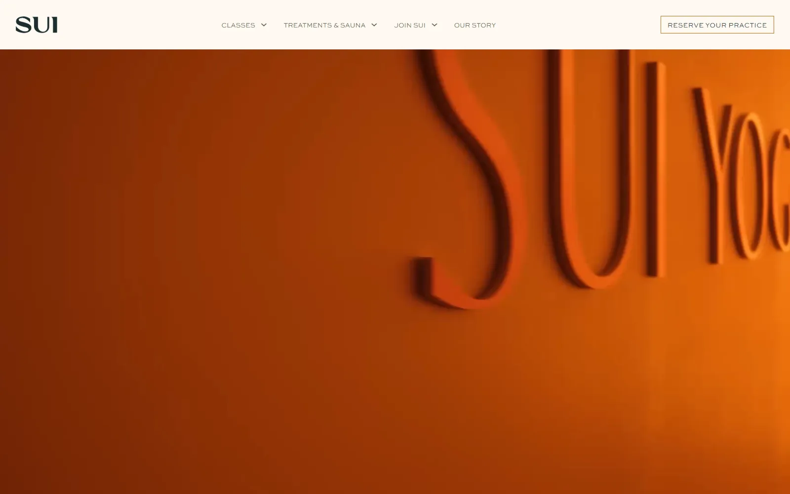 suiyoga.com, yoga studio website design: a burnt orange wall fills the frame with dimensional SUI YOGA lettering raking across it